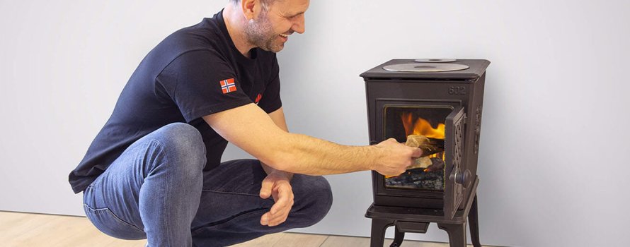 man puts wood in the wood stove jøtul f 602