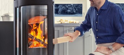 Man put wood in fireplace. Photo.