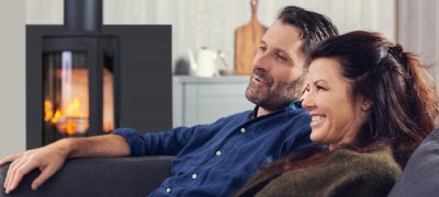 Man and woman sitting in front of the wood stove Jøtul F 373 Advance in the living room 