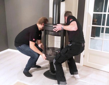 Two men mounting a Jøtul wood stove