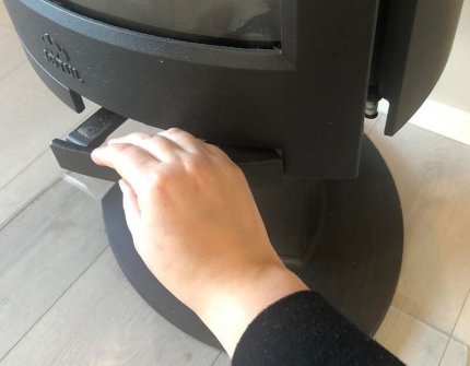 The hand which open the door of the wood stove carefully 