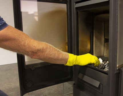 Man cleaning the wood stove Jøtul F 233 with ash and water 