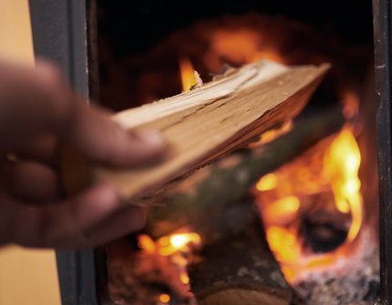 Hand that holding the firewood and putting them into the fireplace