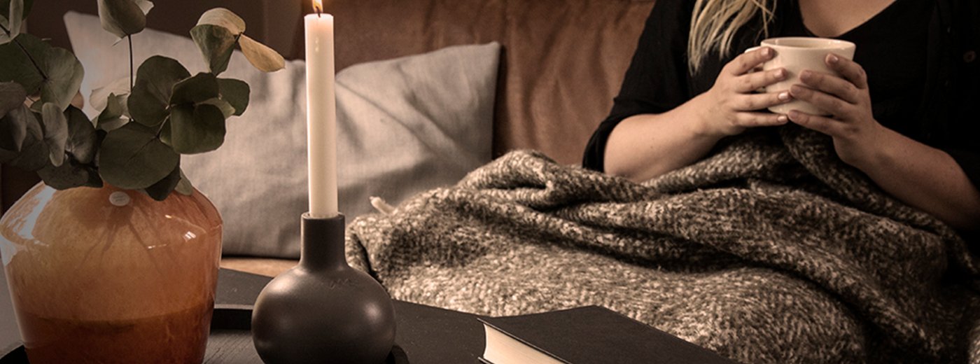 Woman in a sofa with blanket and a warm cup of tea