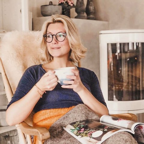 @mesrobes woman sits and enjoys a cup of tea in front of the white Jøtul F 373 Advance stove